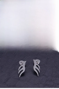 Detailed view of silver flame totem stud earrings on black crocodile leather texture