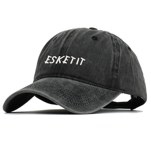 Detail of white ESKETIT embroidery on a washed black cotton six-panel baseball cap