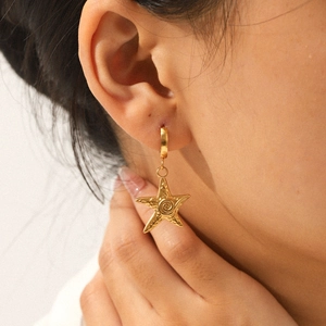 Elegant gold starfish stud earrings made of stainless steel on a female model's ear
