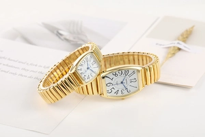 Détail d'une montre à quartz dorée de forme tonneau avec bracelet extensible en métal doré