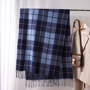 Detailed view of long blue plaid scarf with tassels and soft cashmere-like texture