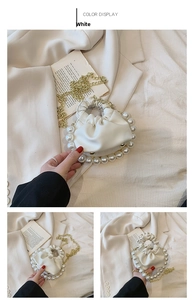 Detail of white pleated faux leather handbag with elegant pearl accents and gold chain strap