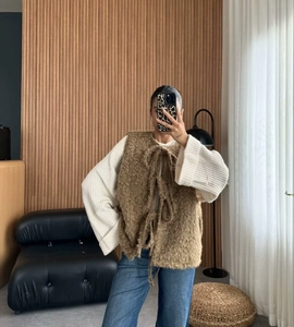 Brown fuzzy knit vest with tie-front detail over a white top and blue jeans