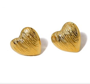 Close-up of heart-shaped gold earrings with brushed metallic texture on white background