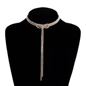 Luxury rhinestone bow necklace with long gold tassel displayed on a black model bust