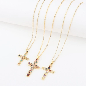 Detailed view of three gold-plated cross necklaces with colorful zircon stones on white base