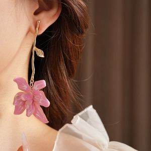 Close-up of pink flower earrings with gold metal leaf details worn by a model