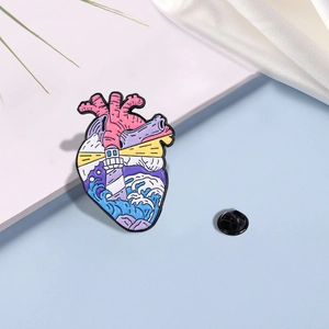 Enamel brooch with anatomical heart design featuring a lighthouse and ocean waves