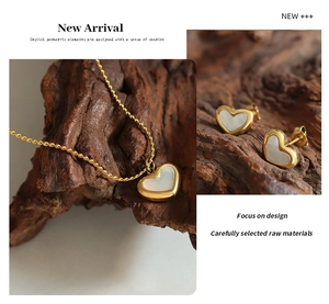 Detail showing a golden heart jewelry set with white shell inlay on natural wood