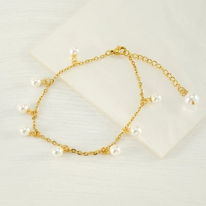 18K gold plated stainless steel anklet with white pearls on a textured white surface