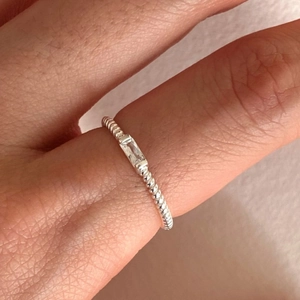 Detailed close-up of a twisted silver ring featuring a sparkling rectangular clear stone