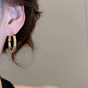 Close-up of a model wearing minimalist golden resin hoop earrings for casual style