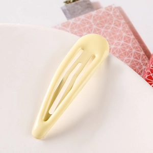 Close-up of a smooth pastel yellow snap hair clip on a minimalist white circular display