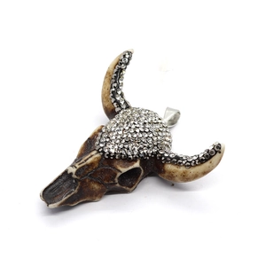 Close-up of brown resin bull skull pendant featuring sparkling rhinestone details and a silver bail