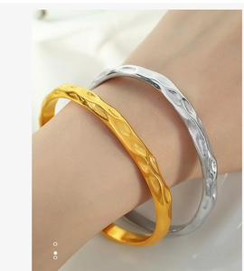 Detail of gold and silver hammered metal bangles with irregular textures on a female wrist