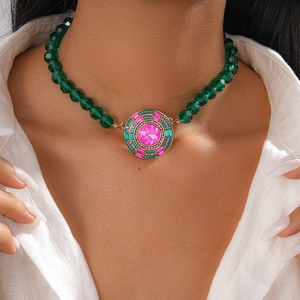 Gros plan sur un collier ras de cou vintage doré avec cristal rose et perles vertes