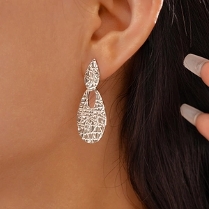 Detail of silver drop earrings with crumpled texture on model for elegant fashion look