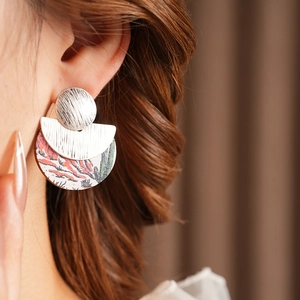 Close-up of minimalist wood drop earrings with desert cactus print and silver studs