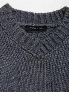 Detailed close-up of dark grey round neck knit sweater featuring a ribbed collar and woven label