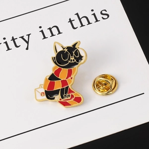 Detail of black cat enamel pin with red-yellow scarf on a white envelope and back clasp