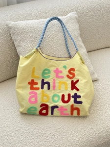 Yellow canvas tote bag with embroidered letters and blue checkered woven handles