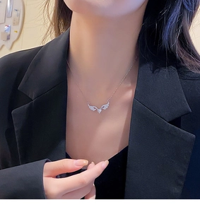 Macro shot of silver angel wing pendant with heart zircon on a model wearing black suit