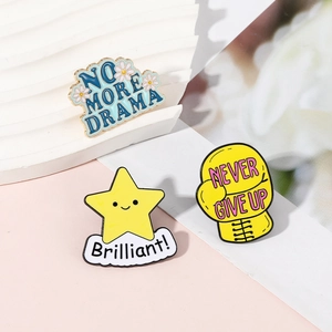 Three enamel pins featuring No More Drama flower, Brilliant star, and Never Give Up boxing glove