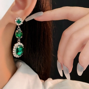 Gros plan de boucles d'oreilles vintage en cristal émeraude avec halo de diamants brillants