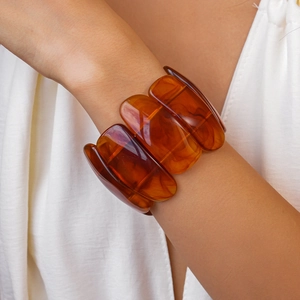 Close-up of wide amber acrylic resin bracelet with marbled texture on a model wrist