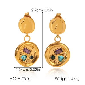 Detail of gold geometric earrings with colorful inlaid crystals and hammered texture