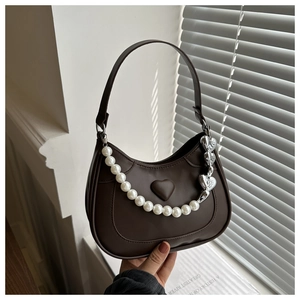 Close-up of brown leather bag with embossed heart and large pearl bead strap detail