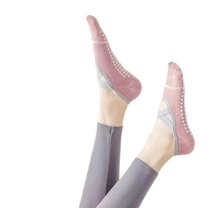 Pink yoga socks with grey cross straps and white non-slip silicone grips on bottom
