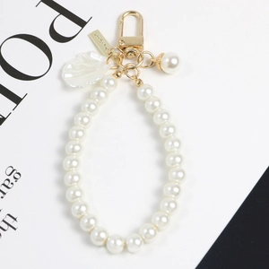 Détails macro du porte-clés en perles blanches avec pendentif coquille et boucle dorée