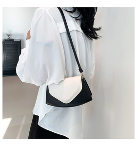 Détail d'un sac bandoulière minimaliste en cuir PU noir et blanc sur un mannequin