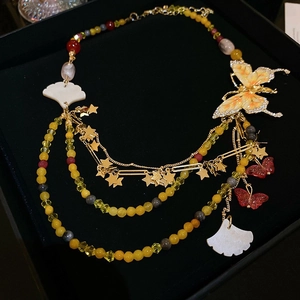 Detailaufnahme der mehrlagigen Perlenkette mit Strass-Schmetterling und Sternquasten