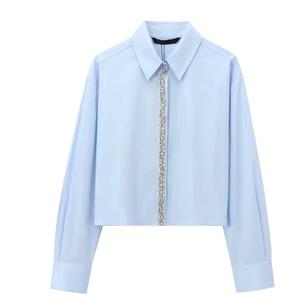 Detail of light blue poplin shirt featuring rhinestone embellishments on the front placket