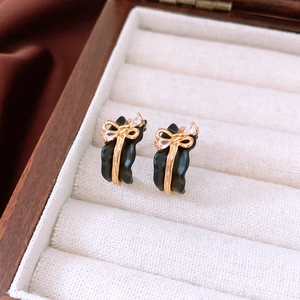 Detail of 18k gold plated black bow earrings with tiny crystals in a wooden jewelry box