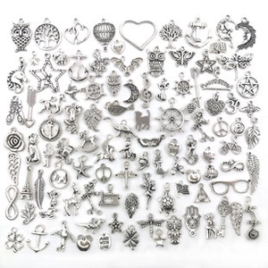 Close-up of mixed silver alloy charms for jewelry making featuring owl and heart designs