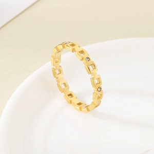 Nahaufnahme eines goldenen hohlen Kettenrings mit Diamanten auf weißem Porzellan