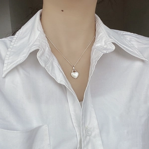 Macro detail of S925 sterling silver heart locket necklace on white shirt model