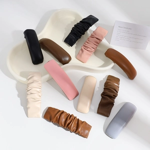 Detailed view of assorted PU leather hair clips featuring smooth and pleated textures on a tray