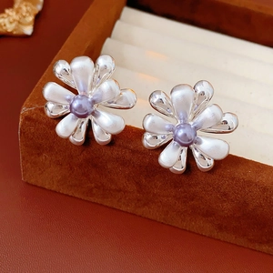 Detailed macro of flower earrings with silver petals and purple pearls in a velvet box