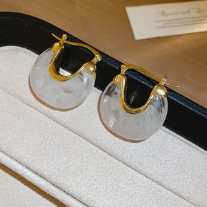 Détail macro de boucles d'oreilles rétro françaises en résine dorée sur un plateau