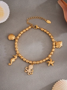 Detalle de la pulsera oceánica de acero inoxidable dorado con dijes de estrellas