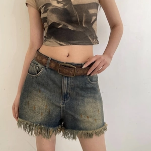 Vintage embossed brown leather belt with distressed denim shorts in Y2K style