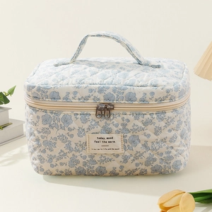 Close-up detail of quilted cotton makeup bag featuring blue floral print and label