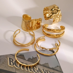 Detail view of a 6-piece golden bangle set featuring pearl accents and hammered texture