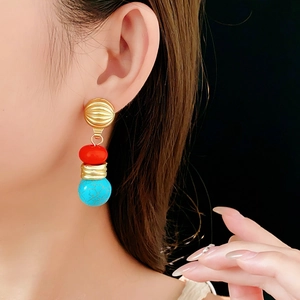 Detail of vintage geometric earrings with red and turquoise beads on female model