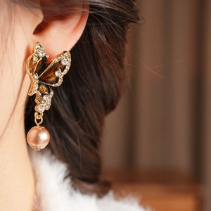 Detailed view of vintage butterfly earring with brown inlay, rhinestones and pink pearl