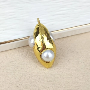 Macro detail of gold plated hammered metal pendant with two natural white round pearls